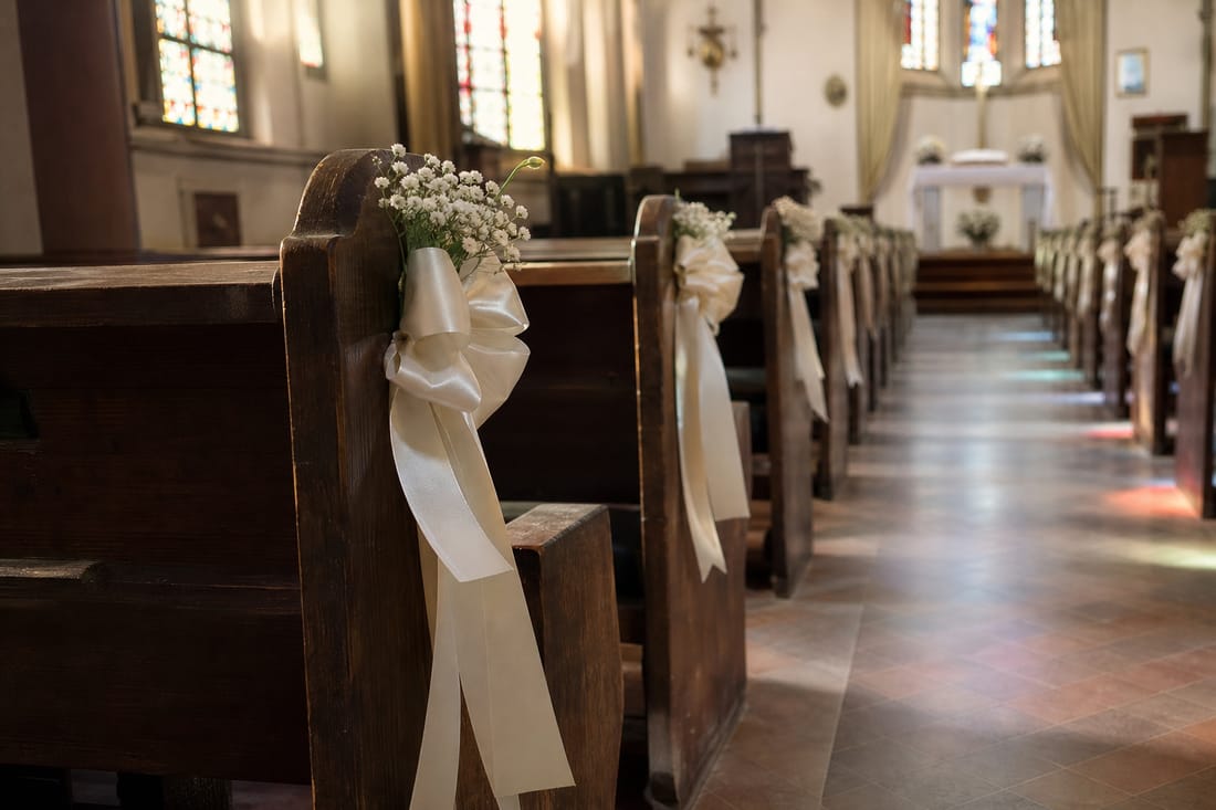 Beispiel: leere Kirchenbankreihe mit Bändern und Blumen